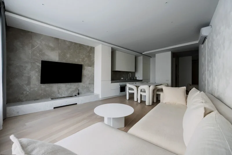 Кухня-гостиная HUMO ARCHITECTS с белым диваном и круглым столиком.